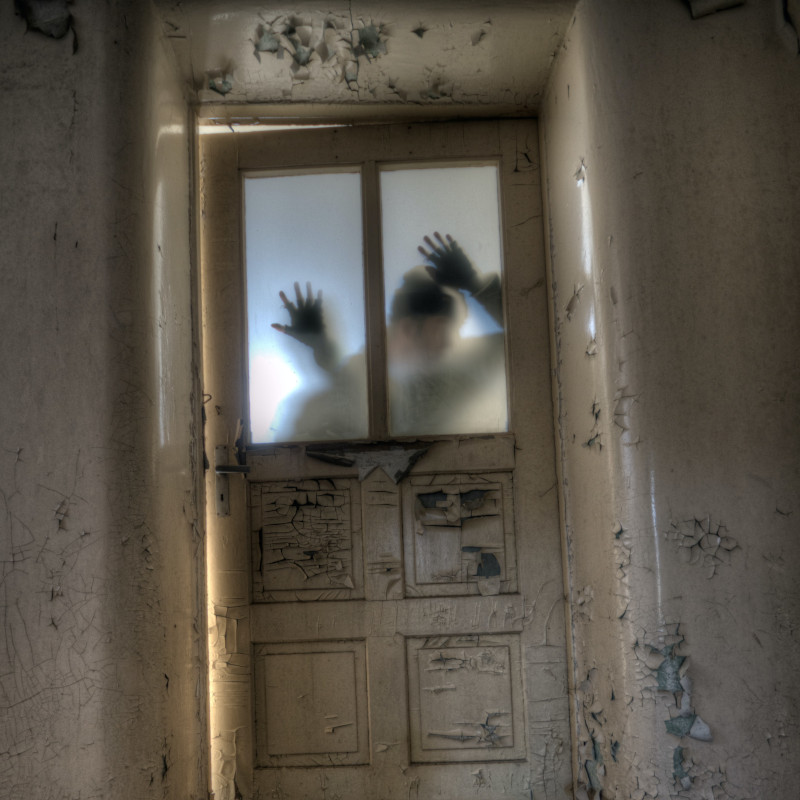 Una persona mira a través de una ventana en un ambiente turbio